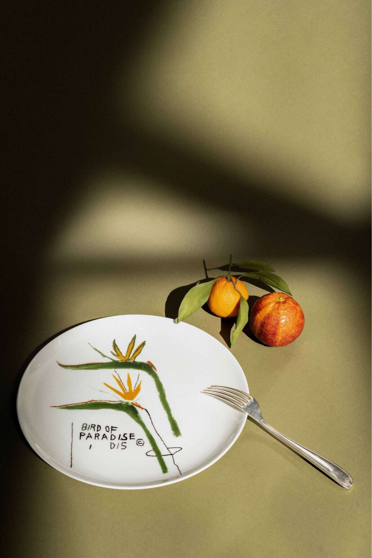 Artist image on plate with cutlery and oranges in display